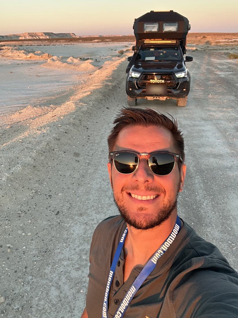 Nicholas Antignolo on a desert track at sunset, with the NickOverlander Hilux behind